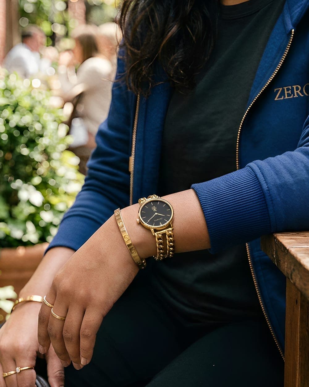 The Zero129 twin-chain watch worn with a gold cuff and a cobalt Zero129 zip hoodie