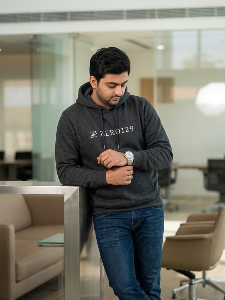 Shikhar Khurana in a charcoal Zero129 hoodie with the monogram wordmark, checking his watch